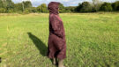Lady wears LeMieux All Elements Robe in a field with the hood up, viewed from the side