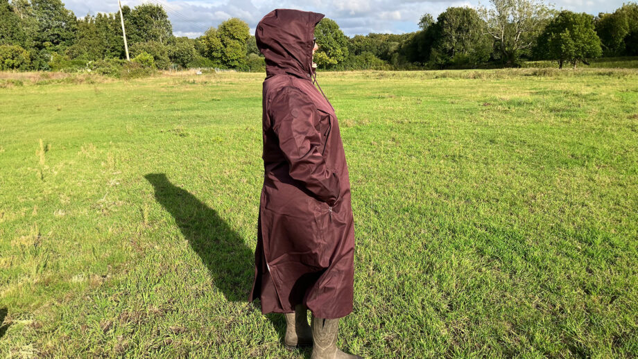 Lady wears LeMieux All Elements Robe in a field with the hood up, viewed from the side
