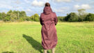 Lady wears LeMieux All Elements Robe in a field, viewed from the back