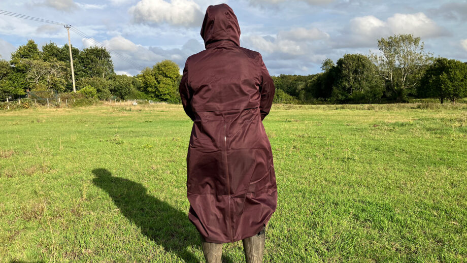 Lady wears LeMieux All Elements Robe in a field with the hood up, viewed from the back