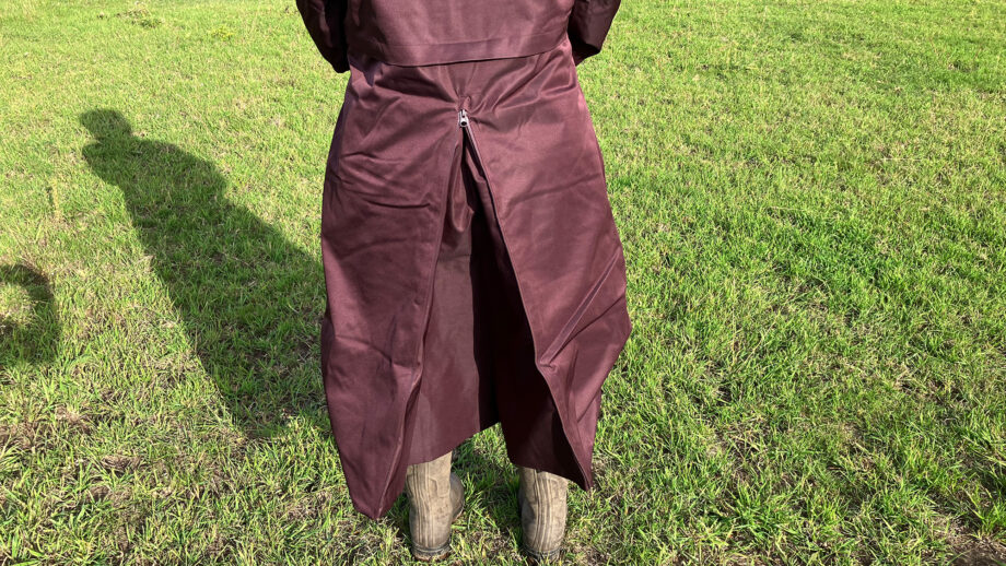 Lady wears LeMieux All Elements Robe in a field, close up of riding vent viewed from the back