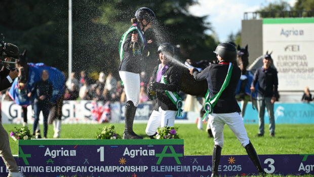 Laura Collett stands on the Blenheim Europeans podium while being sprayed with Champagne by Michael Jung and Tom McEwen.