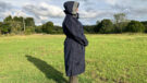 Lady wears Reincoat Lite with the hood up, viewed from the side