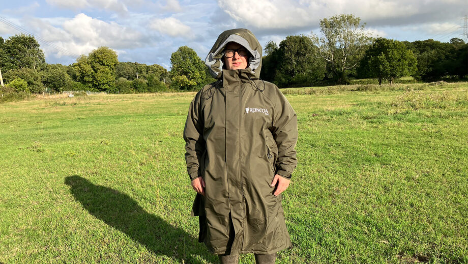 Lady wears Reincoat Pro in a field with hood up, viewed from the front