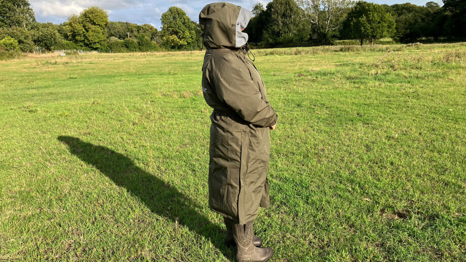 Lady wears Reincoat Pro in a field with hood up, viewed from the side