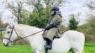Rider wears Reincoat Pro Robe on a horse, viewed from the side