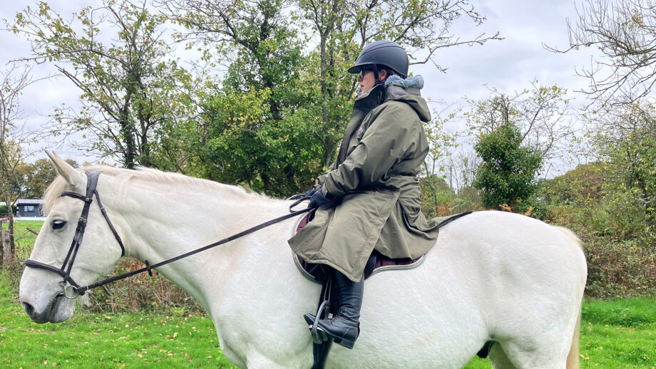 Rider wears Reincoat Pro Robe on a horse, viewed from the side