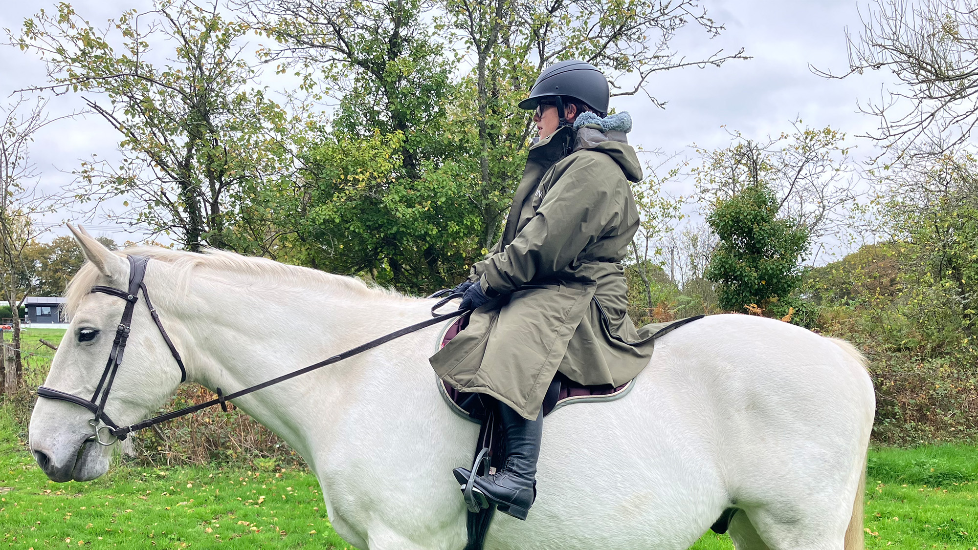 Rider wears Reincoat Pro on horse, viewed from the side