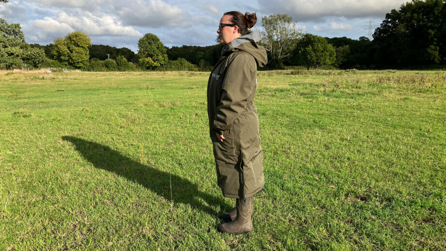 Lady wears Reincoat Pro in a field, viewed from the side