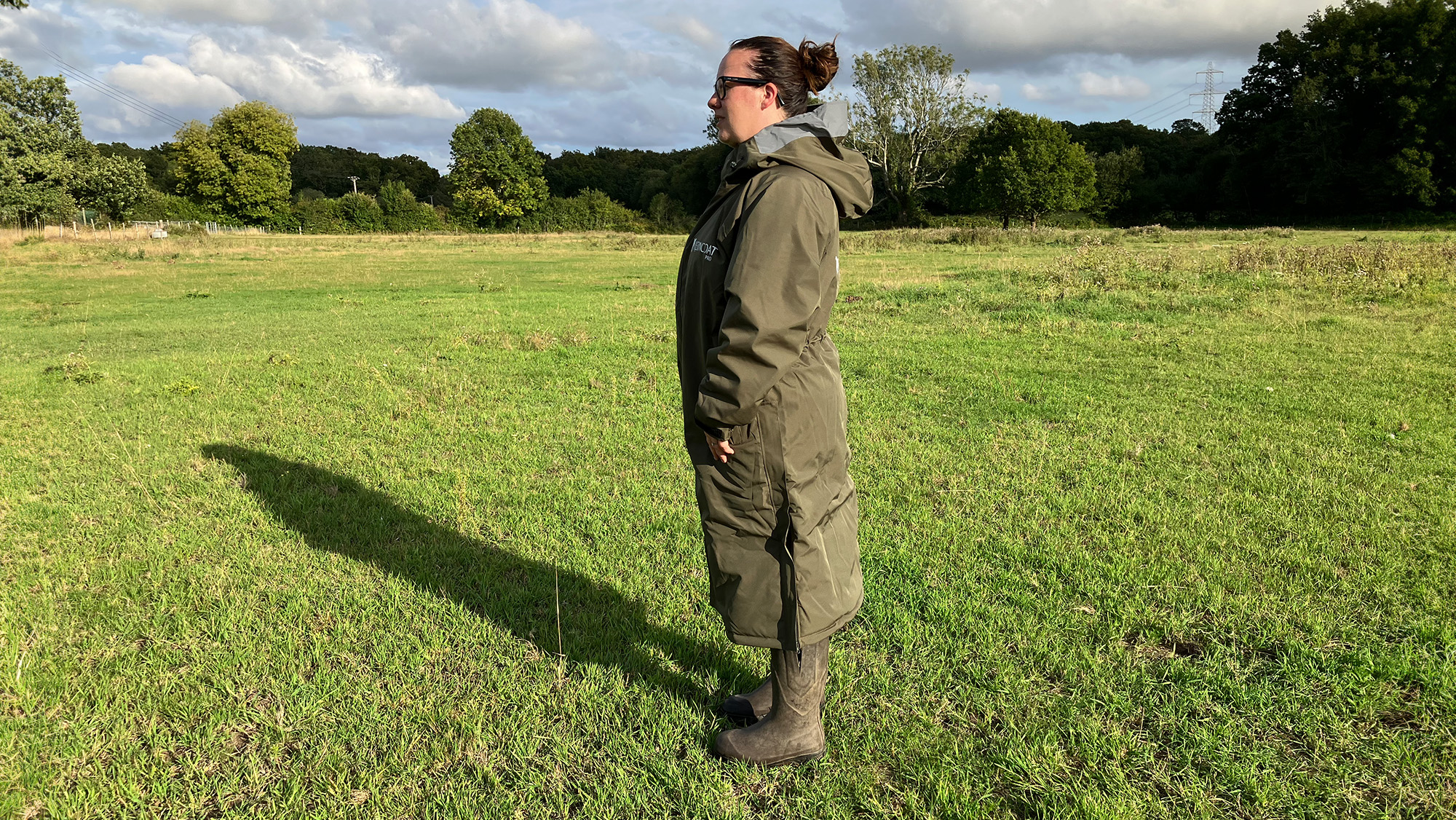Lady wears Reincoat Pro in a field, viewed from the side