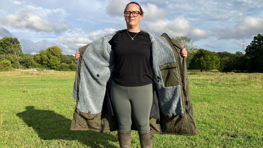 Lady wears Reincoat Pro in a field unzipped showining lining, viewed from the front