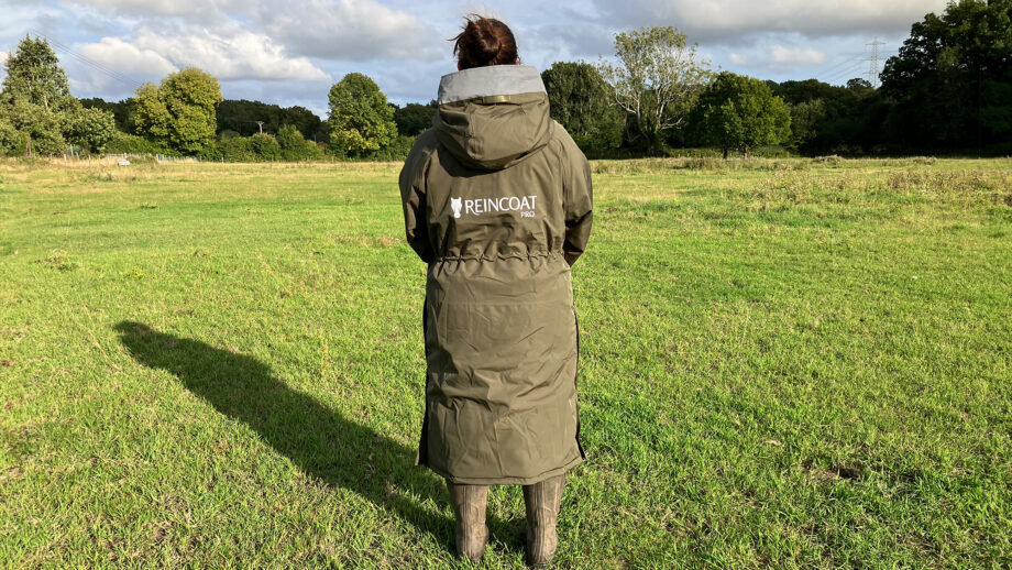 Lady wears Reincoat Pro in a field, viewed from the back