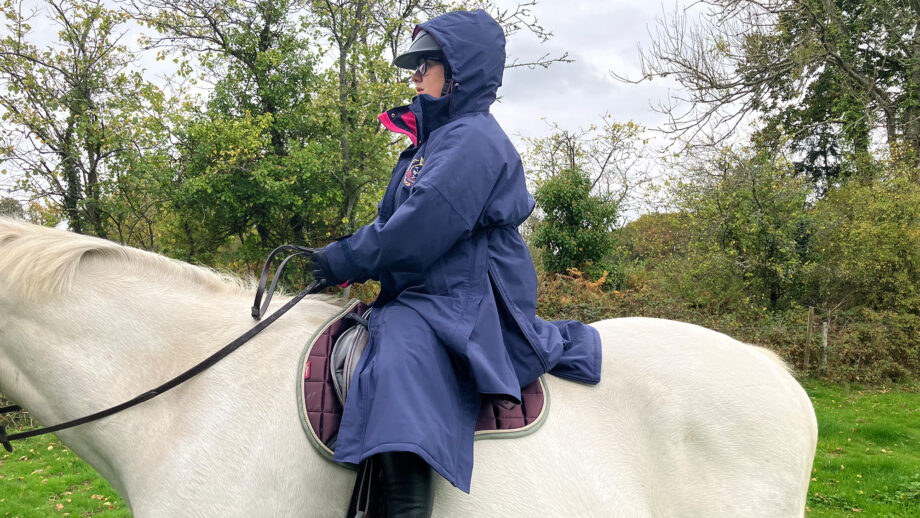 Rider wears Rydale Utility Changing Robe on a horse with the hood up, viewed from the side
