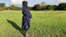 Lady wears Rydale Utility Changing Robe in a field with the hood up, viewed from the side