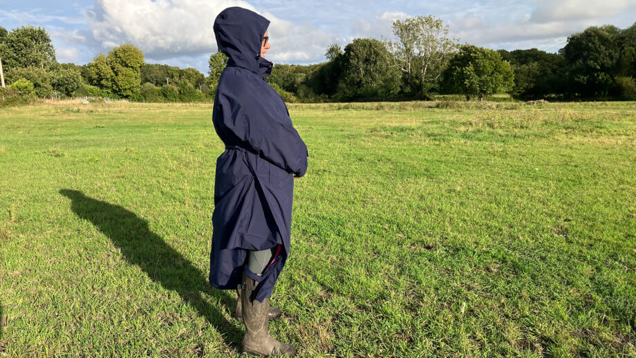 Lady wears Rydale Utility Changing Robe in a field with the hood up, viewed from the side