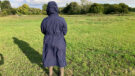 Lady wears Rydale Utility Changing Robe in a field with the hood up, viewed from the back
