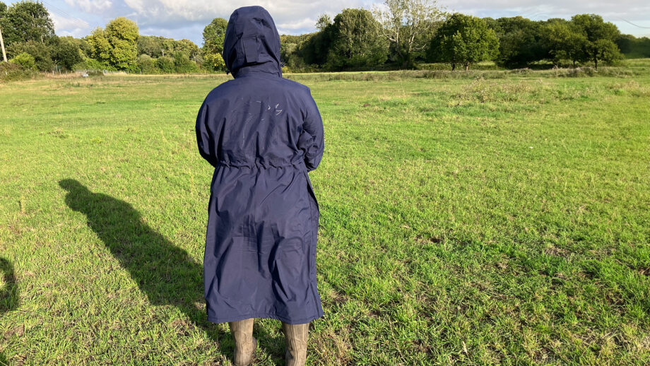 Lady wears Rydale Utility Changing Robe in a field with the hood up, viewed from the back