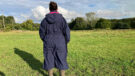 Lady wears Rydale Utility Changing Robe in a field, viewed from the back
