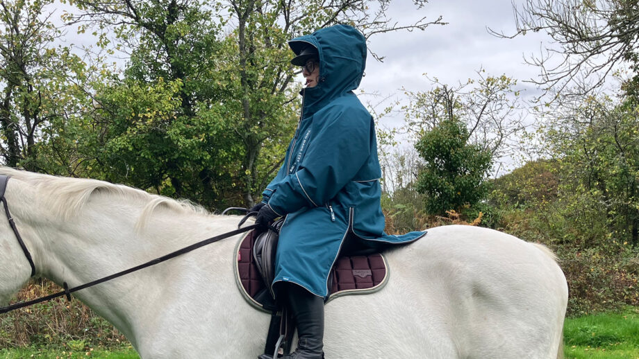 Rider wears Two Bare Feet Hi-Vis Lightweight Riding Robe on a horse with the hood up, viewed from the side