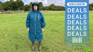 Fran wearing the Two Bear Feet riding coat in a field, with the H&H deals graphic overlayed