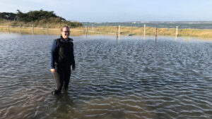 Fran wearing her aigle wellies wading through a high tide flood in her field