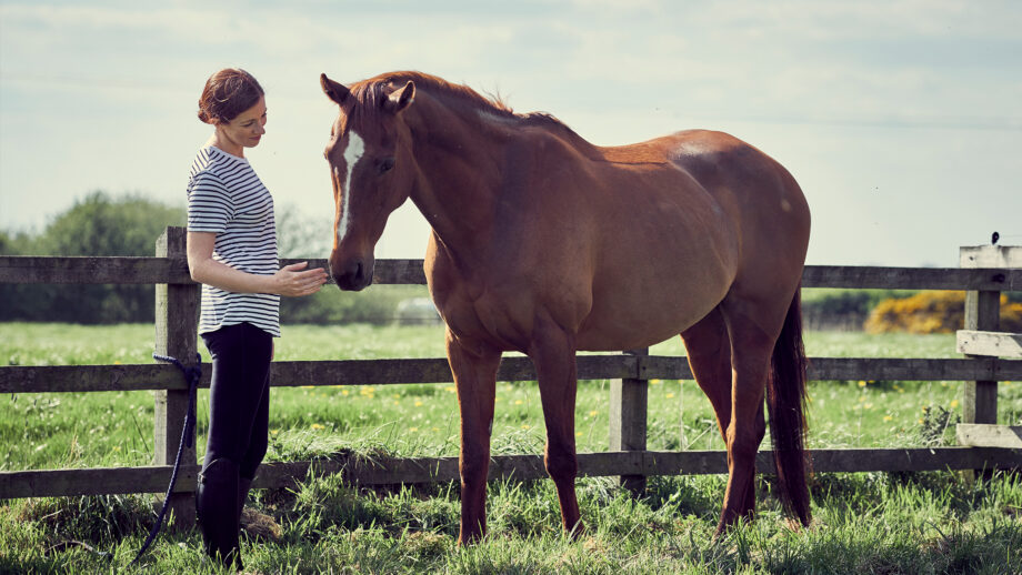 Woman with partially sighted horse in the field