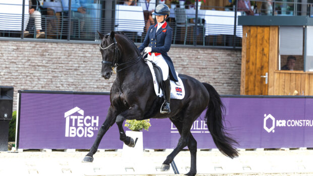 Lottie Fry and Glamourdale canter alongside the dressage board at the FEI Dressage European Championship 2025 in France.