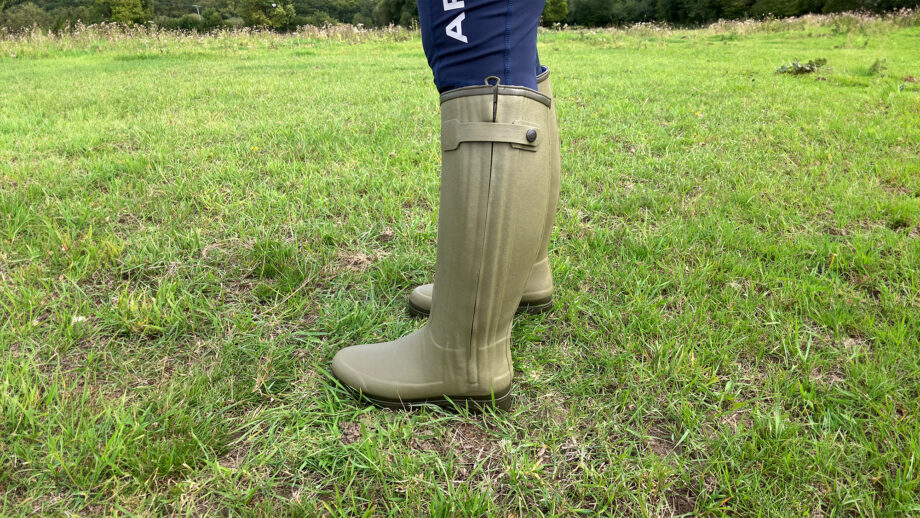 Side view of model wearing Le Chameau Chasseur Neoprene wellies in a field