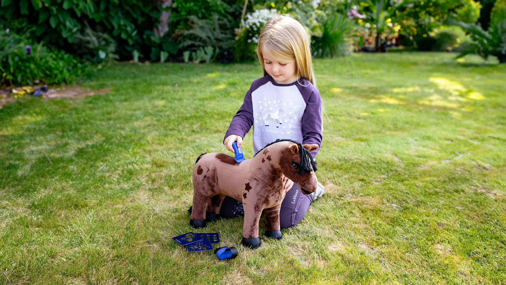 Litte girl playing with a LeMieux Toy Pony Gracie in the garden