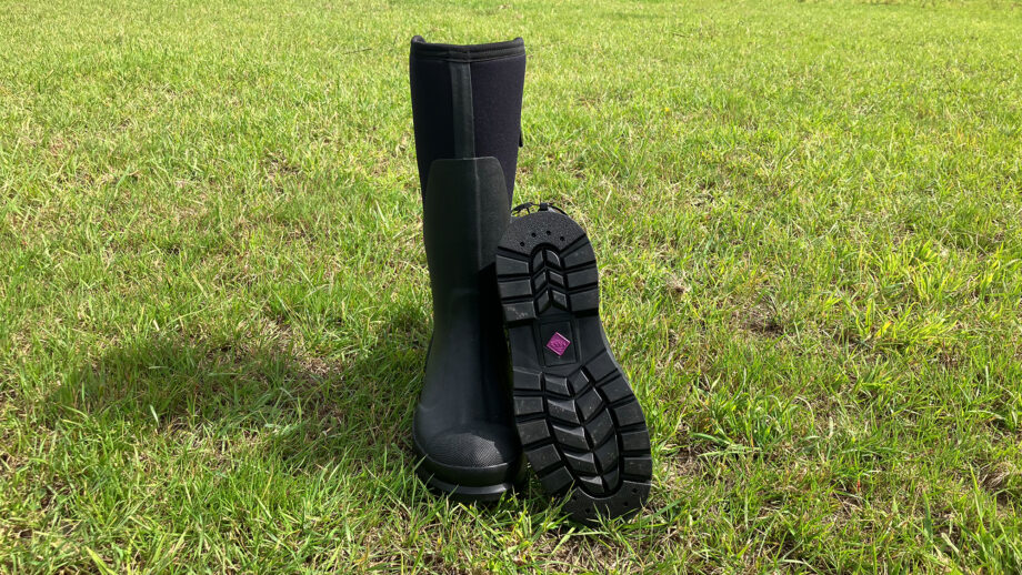 Muck Boot Women’s Chore Adjustable Tall Boots front view in field with one showing footbed