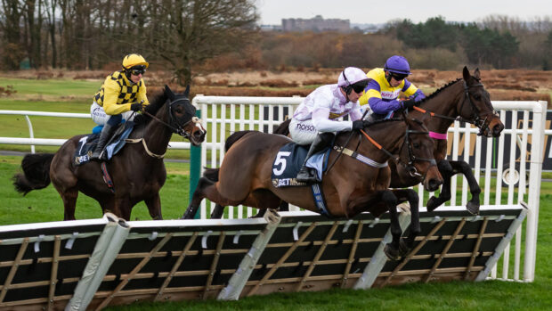 Three horses jump a hurdle during the Fighting Fifth Hurdle at Newcastle.