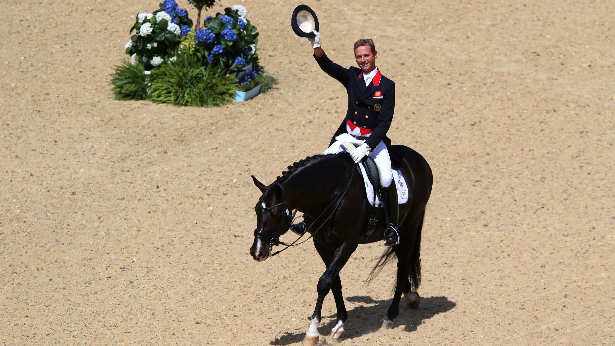 Uthopia, a black stallion ridden by Carl Hester. Carl Waves from the dressage arena with his top hat in hand at the London 2012 Olympic Games.