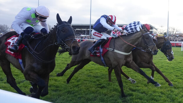 Three racehorses at full gallop in the Ladbrokes King George VI Chase at Kempton Park