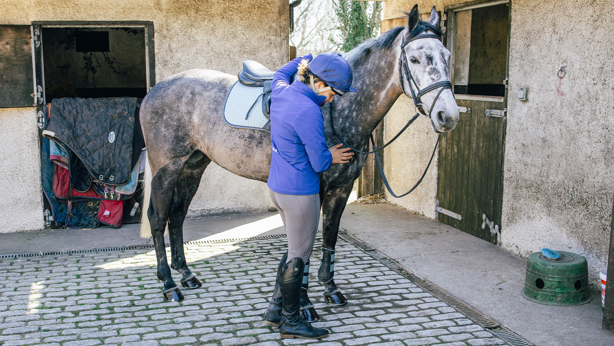 Horse rider stood by horse looking down and stressed