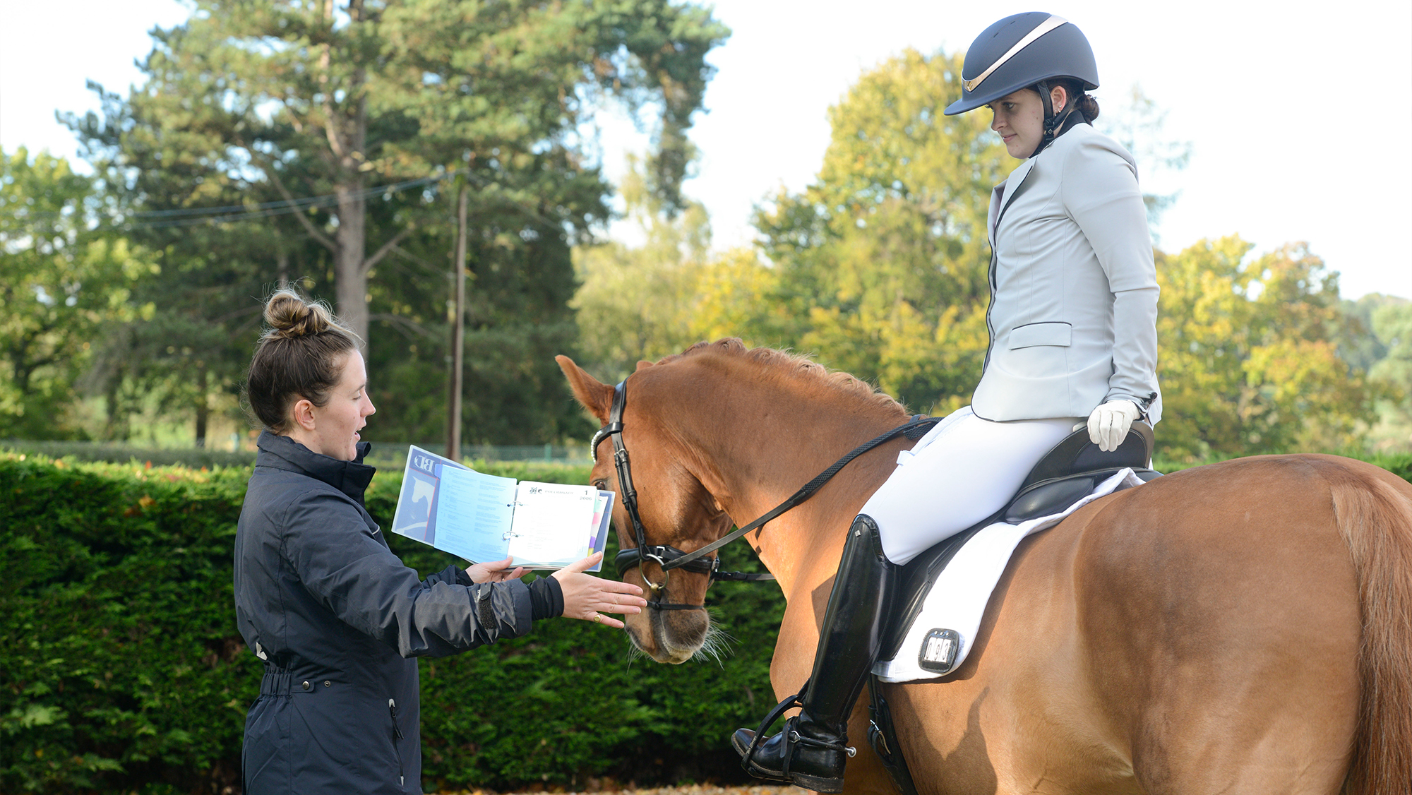 Coach or instructor giving feedback to competitive rider on horse
