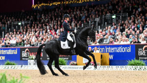Charlotte Fry rides a canter pirouette on Glamourdale in front of the packed stands at London International Horse Show 2024.