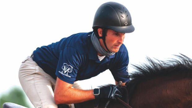 A close up image of Andrew McConnon in jumping position on a bay horse.