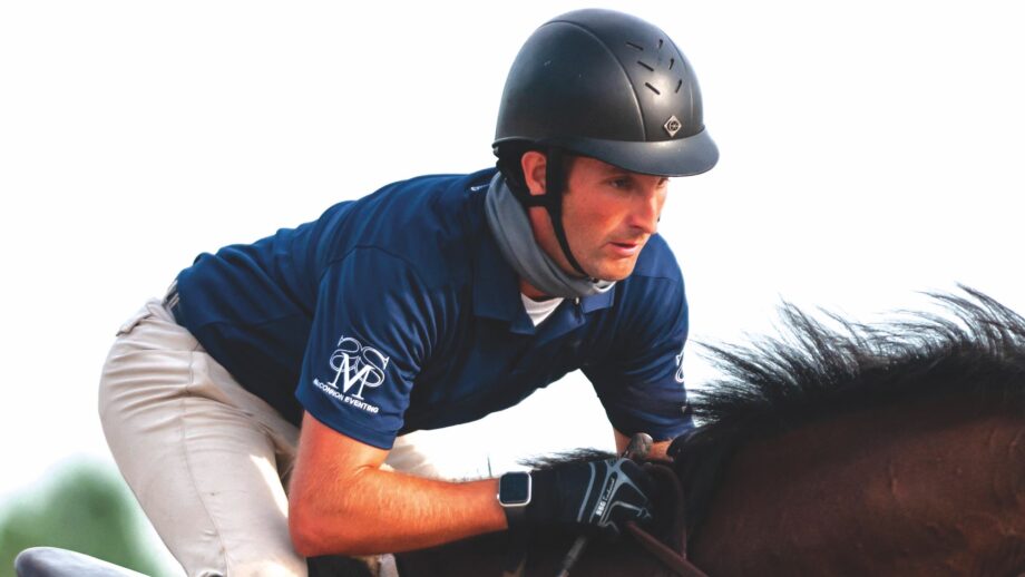 A close up image of Andrew McConnon in jumping position on a bay horse.