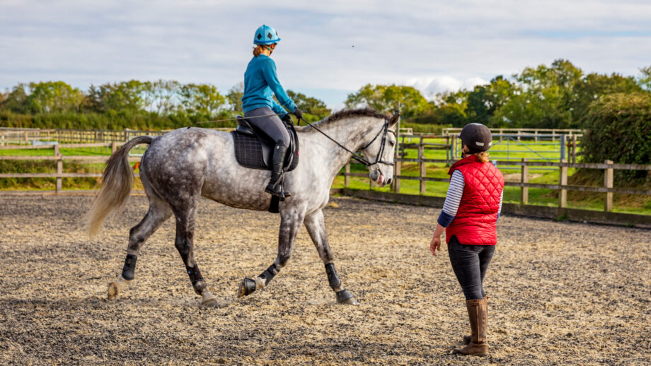 Horse rider wearing horse riding clothes and learning to ride with teacher in the foreground