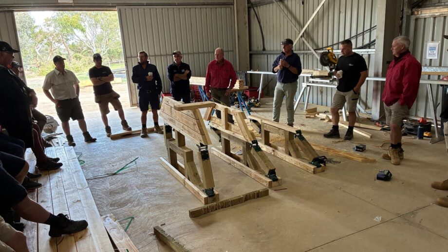 Image shows a group of people in a shed, looking at components for a new-age deformable fence during a seminar on frangible fences in Australia in January 2026.