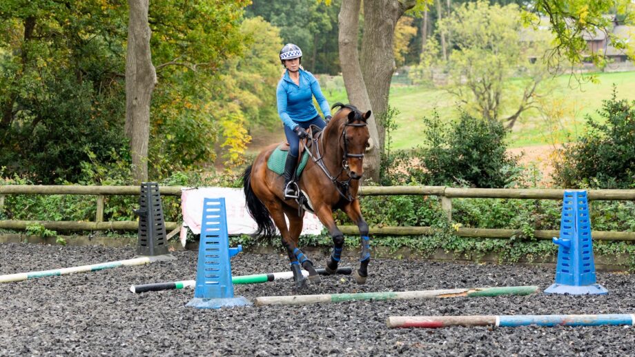 Event rider Vittoria Panizzon on a bay horse demonstrates a polework exercise for suppleness in an arena using ground poles