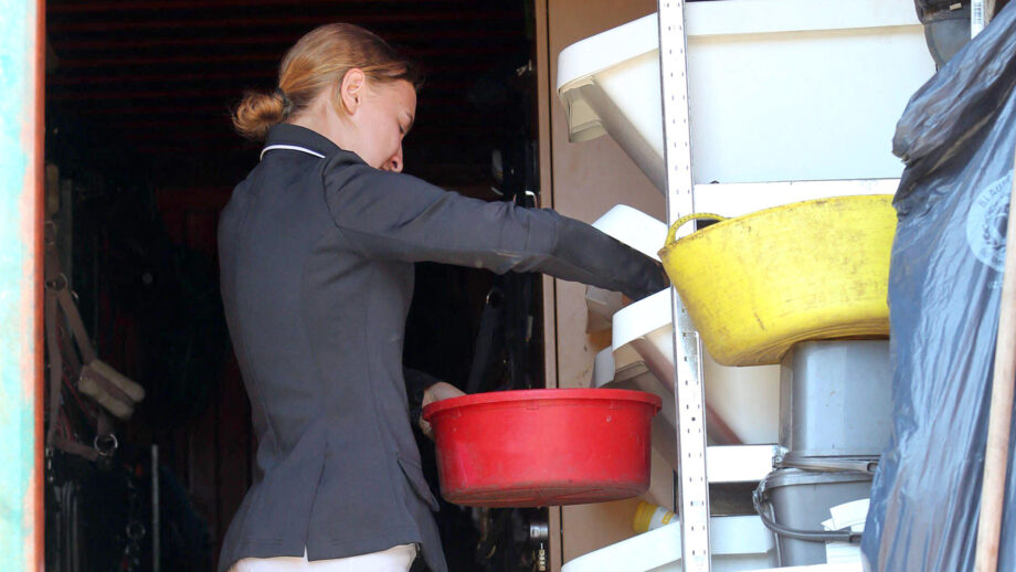 Rider wearing competition gear preparing feed for her performance horse