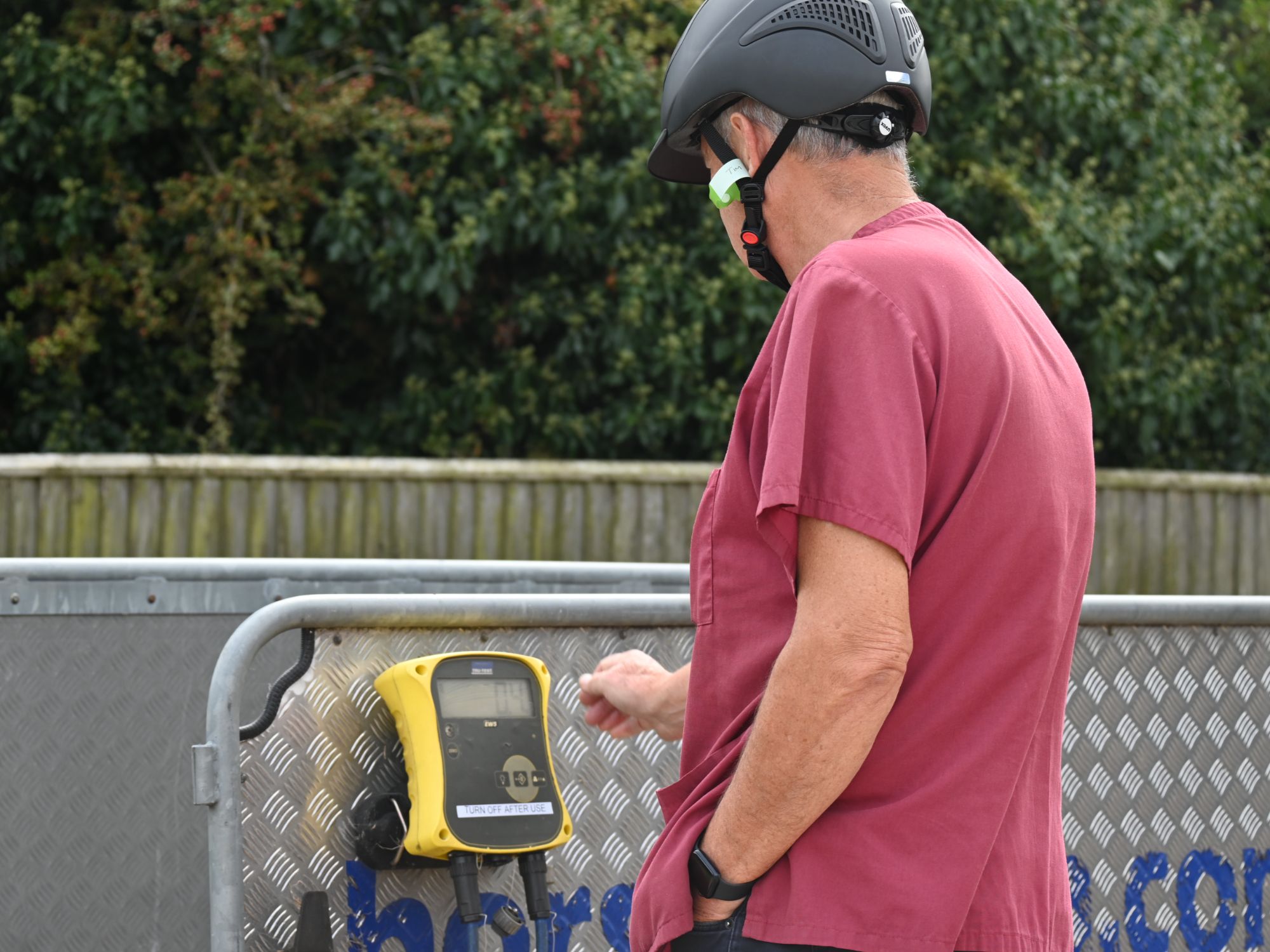 A man wearing a read tshirt and safety helmet calibrates a weighbridge.