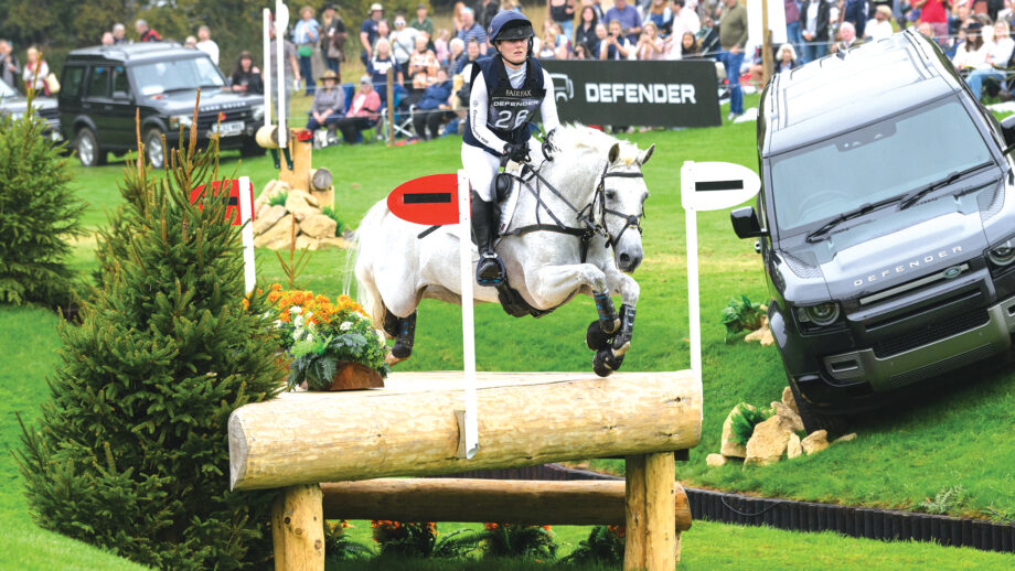 Pictured five-star rider Libby Seed and her grey horse Heartbreaker Star Quality jumping a cross-country fence at Burghley Horse Trials in 2024.