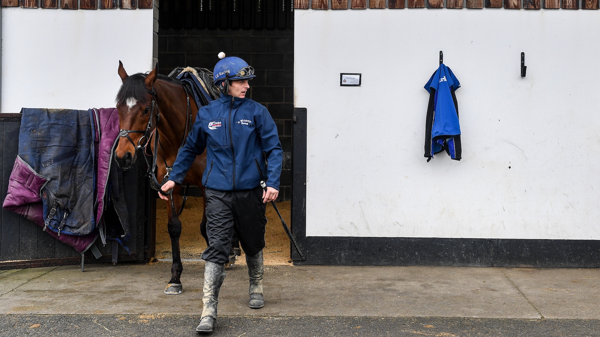 Bay horse with start walking out of stable at racing yard