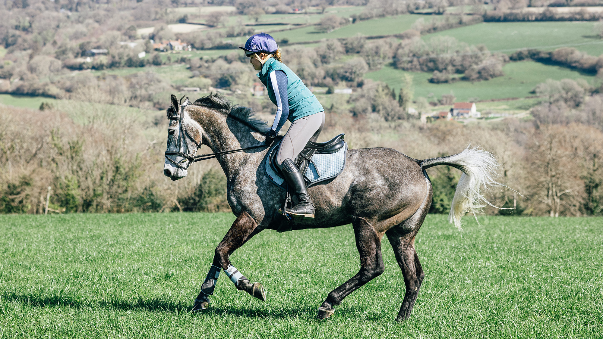 Rider cantering grey horse in a field to prepare for competition