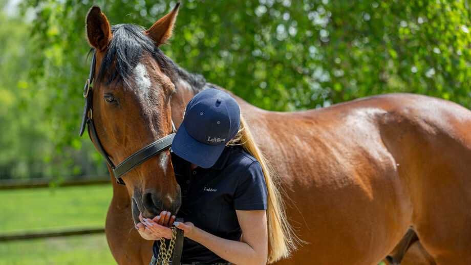 Unidentified female cuddling her own bay horse