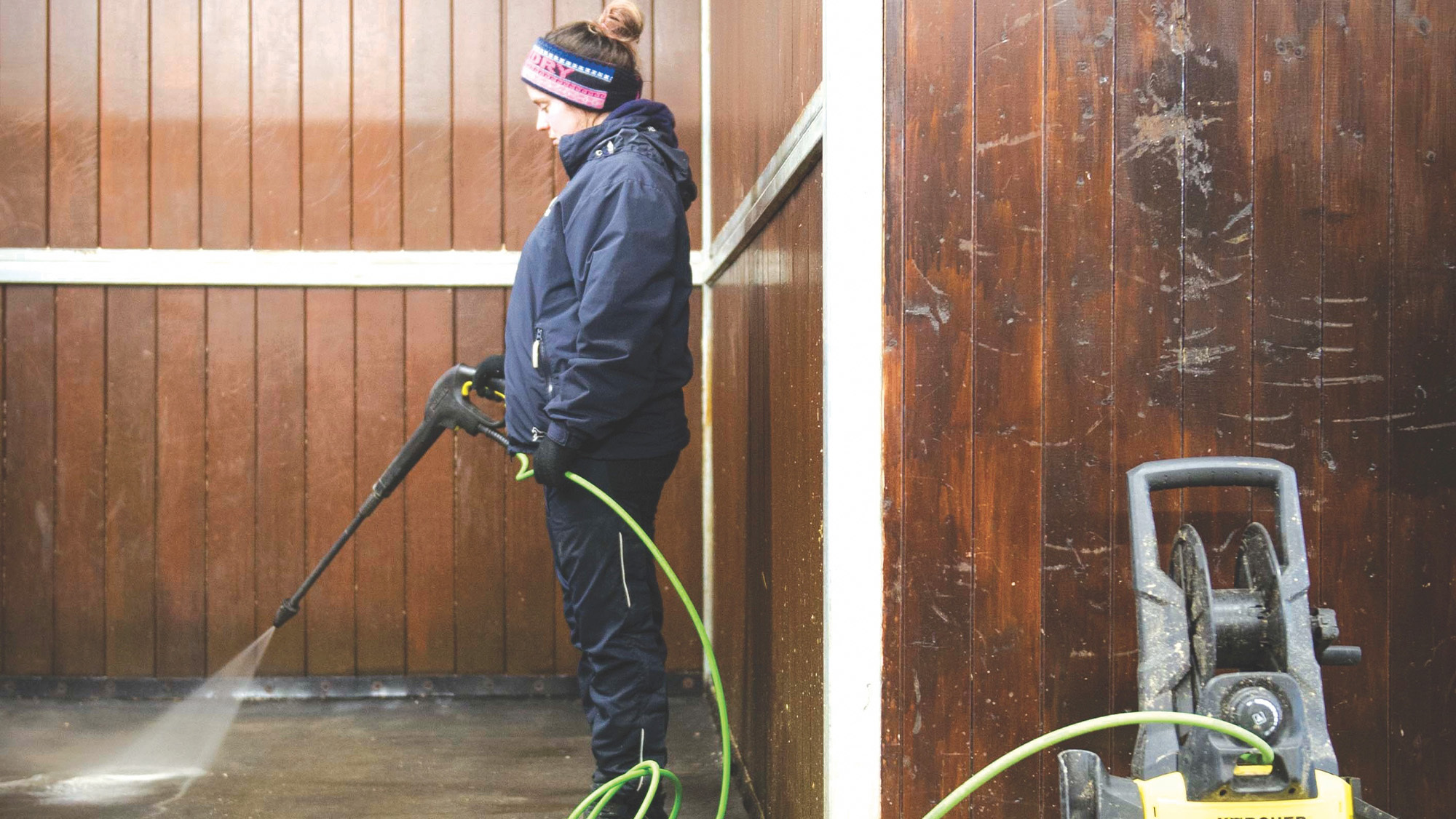 Groom disinfecting a stable at an equine hospital
