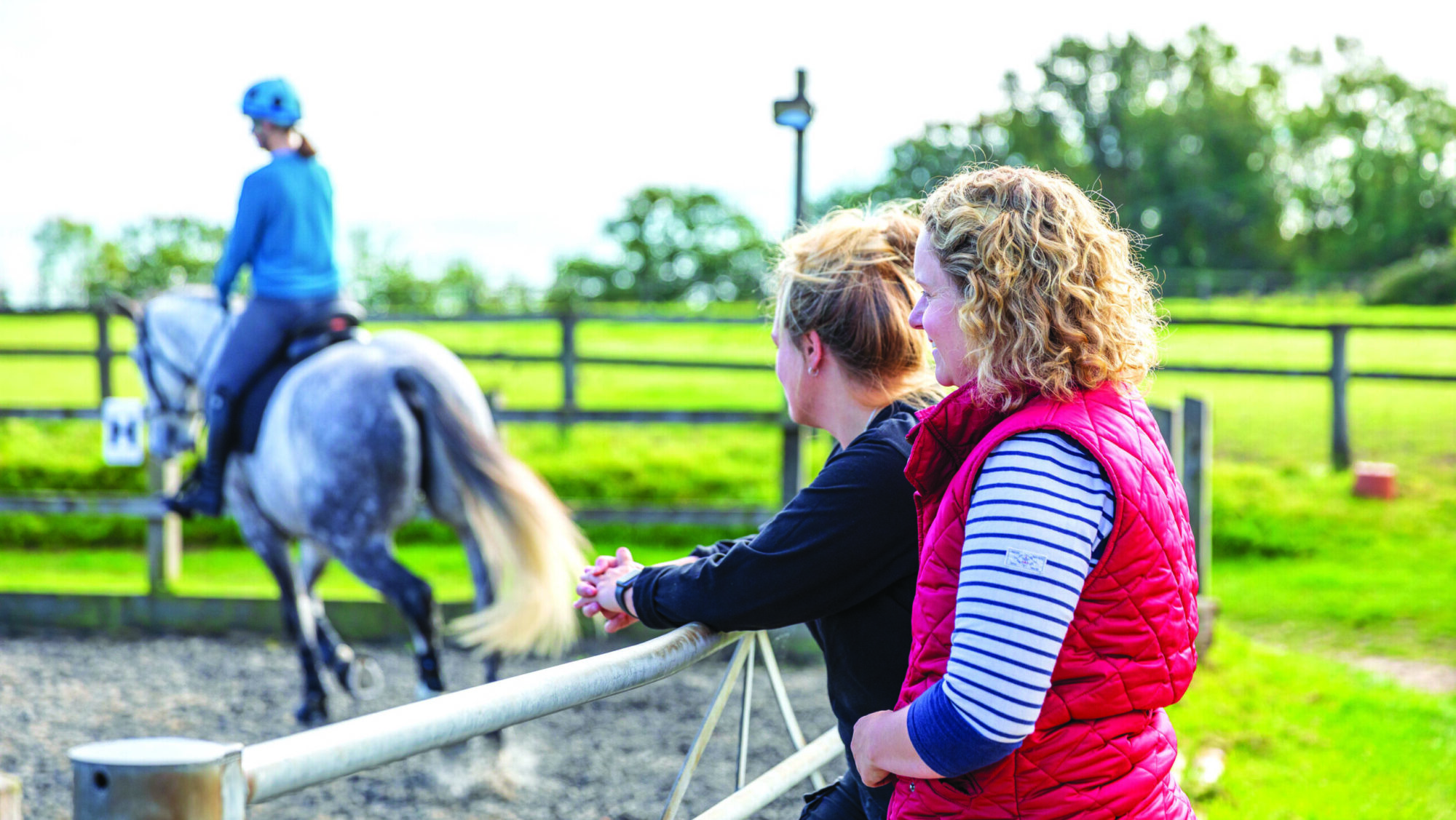 Two women watching horse being ridden at a sales livery
