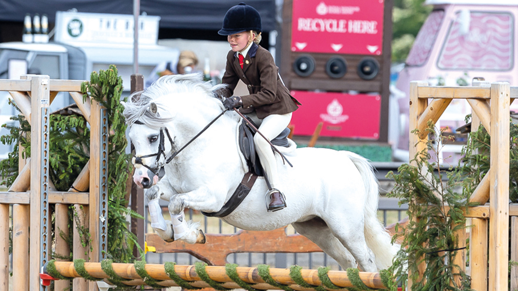 Poppy Rowlands jumps M&M working hunter pony Delami Bravado over a rustic spread at Royal Windsor.
